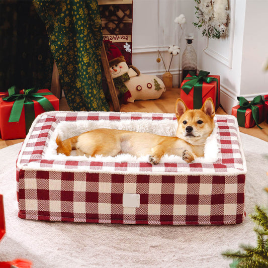 Dog lying on a red and white checkered pet bed with Christmas decorations in the background.